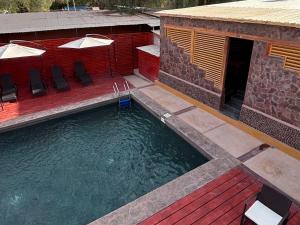 een buitenzwembad met ligstoelen naast een gebouw bij Hotel Toconar in San Pedro de Atacama