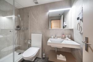 ein Badezimmer mit Waschbecken, Toilette und Dusche in der Unterkunft Hotel Grindelwalderhof in Grindelwald