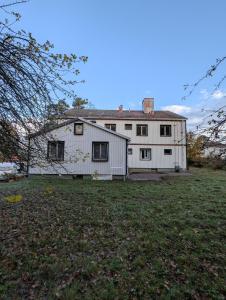 a white house with a yard in front of it at Lägenhet nära naturen Pralinette BB in Nykroppa