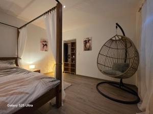a bedroom with a bed and a hanging chair at Appartement de Charme in Bévilard