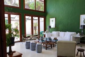 un salon avec un canapé blanc et un mur vert dans l'établissement Pousada Vila Corada, à Pipa