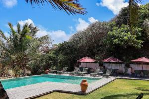 ein Pool mit Stühlen und Sonnenschirmen neben einem Resort in der Unterkunft Pousada Vila Corada in Pipa
