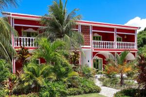 une maison rouge avec des palmiers devant dans l'établissement Pousada Vila Corada, à Pipa
