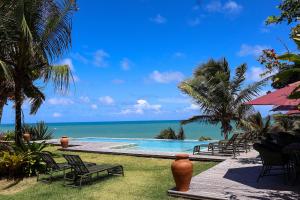 a pool with chairs and the ocean in the background at Pousada Vila Corada in Pipa +159 photos