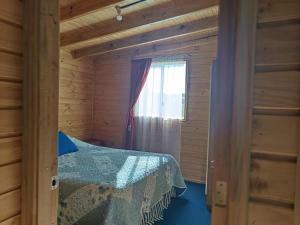 una camera da letto in una baita di tronchi con un letto e una finestra di Refugio Lemuy - Chiloé a Puqueldón