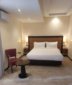 a bedroom with a bed and a chair and a table at Hotel redouane in Marrakech