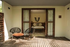 una camera con un letto e due sedie su un portico di Tay Beach Hotel Tayrona a Buritaca Altre 45 foto