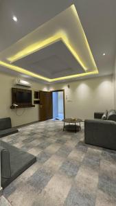a living room with a ceiling with a couch and a table at شقق اركان الريم للوحدات السكنية in Al Thybiyah