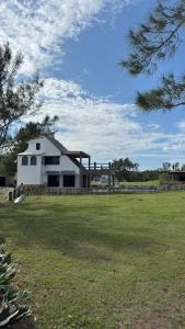 a white barn in a field with a fence at Beach chalet with Private Pool in Heroica Alvarado