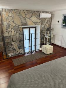 a room with a stone wall with a bed and a window at Rent Room Sardegna in Porto Torres