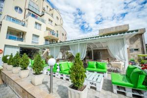 eine Außenterrasse mit grünen Stühlen und einer Pergola in der Unterkunft Apart Hotel Vechna R in Sonnenstrand