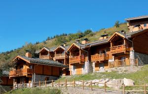 un grupo de edificios de madera en una colina en Résidence Odalys Le Grand Panorama 1 en Valmeinier