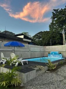 a swimming pool with a blue umbrella and two chairs at Casa B Pasco in Dauin