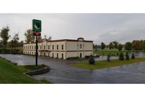 een groot gebouw op een parkeerterrein met een parkeerplaats bij Pleasant Night Inn Watertown by Hotel O in West Carthage