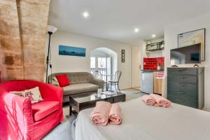 a living room with two beds and a red chair at Studio Alienor Place la Bourse Bordeaux in Bordeaux