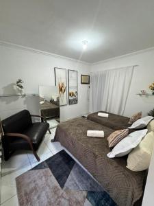 een slaapkamer met een groot bed en een stoel bij Loft Ilha Grande in Angra dos Reis