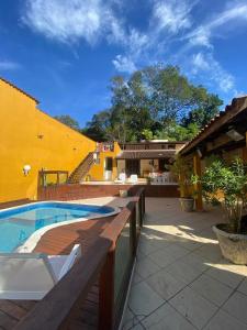 een patio met een zwembad naast een geel gebouw bij Loft Ilha Grande in Angra dos Reis