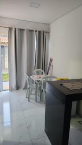 a room with a table and chairs and curtains at kitnets Praia Super in Cumuruxatiba