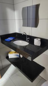 a bathroom counter with a sink and a mirror at kitnets Praia Super in Cumuruxatiba