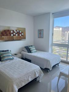 Cette chambre blanche dispose de deux lits et d'une fenêtre. dans l'établissement Resort de Reserva del Mar, à Santa Marta