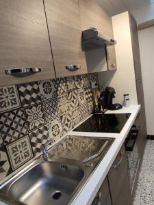 eine Küche mit Spüle und Fliesen an der Wand in der Unterkunft Bienvenue chez Coco in Dunkerque + 35 Fotos