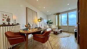 een woonkamer met een tafel en stoelen en een woonkamer bij Vue Paris 1 min de la gare in Saint-Cloud
