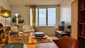 een woonkamer met een tafel en een groot raam bij Vue Paris 1 min de la gare in Saint-Cloud