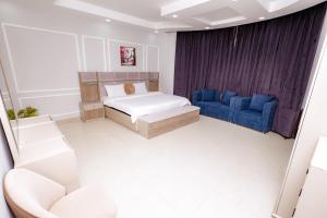a bedroom with a bed and two blue chairs at السعادة نستو - نسائم صلاله للأجنحة والشقق الفاخرة Nassayem Salalah Hotel Apartments & Suites Downtown in Salalah