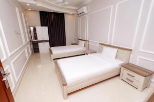 a small room with two beds and a refrigerator at السعادة نستو - نسائم صلاله للأجنحة والشقق الفاخرة Nassayem Salalah Hotel Apartments & Suites Downtown in Salalah +5 photos