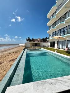 een zwembad naast een strand met een gebouw bij Maraga Bento in Maragogi