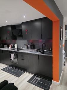 eine Küche mit schwarzen Schränken und einer orangefarbenen Linie in der Unterkunft Energy - 8ight Havens Folkestone in Folkestone