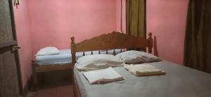 een slaapkamer met twee bedden, witte kussens en roze muren bij Hostel María Ometepe in Santa Cruz