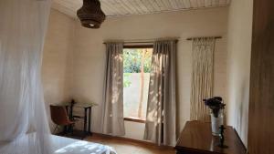 a bedroom with a window and a table with a vase of flowers at Casa Pequi in Alexânia