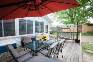 a patio with a glass table and chairs and a red umbrella at Cottage on Crystal Beach 3BR & BBQ in Fort Erie