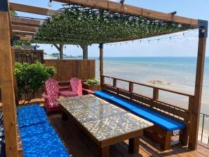 a patio with a table and chairs and the beach at Water Front Beach House - 3BR w BBQ & Sunset in Fort Erie +22 photos