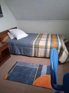 a bedroom with a bed and a chair and a rug at Búho Real Cityhouse in El Cerrillo
