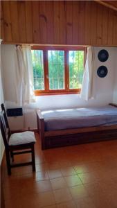 ein Schlafzimmer mit einem Bett und einem Stuhl und Fenstern in der Unterkunft Papacholo in Pinamar