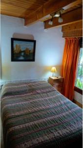 ein Schlafzimmer mit einem Bett und einem Bild an der Wand in der Unterkunft Papacholo in Pinamar