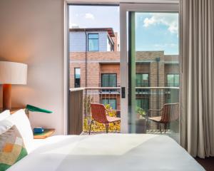 a bedroom with a bed and a balcony with chairs at Hotel Magdalena in Austin