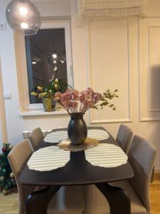 een eettafel met een vaas met bloemen erop bij Stan na dan Bor Apartman in Bor +14 foto's
