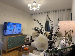 een woonkamer met een vaas met bloemen en een tv bij Stan na dan Bor Apartman in Bor