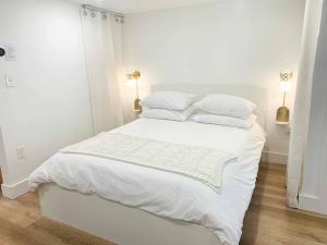 a white bedroom with a white bed with white sheets and pillows at Fresh Modern Garden Level Kittery Studio in Kittery