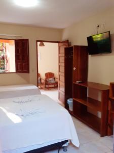 a bedroom with a white bed and a television at Pousada Rota Beach in Porto De Galinhas