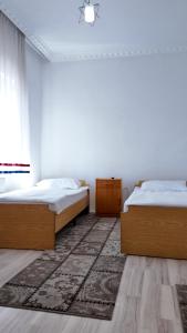 a bedroom with two beds and a rug at Gumus Hotel in Ortahisar