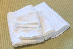 een stapel witte handdoeken zittend op een tafel bij Kulton Moct Kenroku in Kanazawa