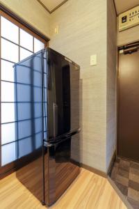 een grote zwarte koelkast in de hoek van een kamer bij Kulton Moct Kenroku in Kanazawa