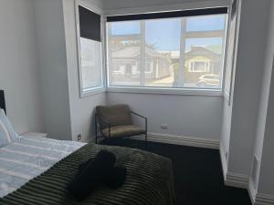 a bedroom with a bed and a chair and a window at Stylish Petone Stay in Lower Hutt