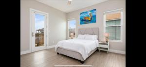 a white bedroom with a bed and two windows at Stunning Beach Front House in Crystal Beach