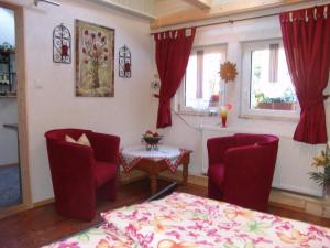 a living room with red chairs and a table and windows at Apartment Spree Idyll by Interhome in Lübbenau
