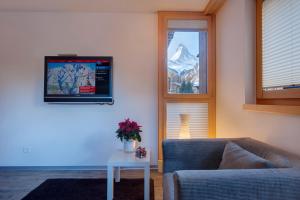 sala de estar con sofá, mesa y ventana en Haus Welcome, en Zermatt